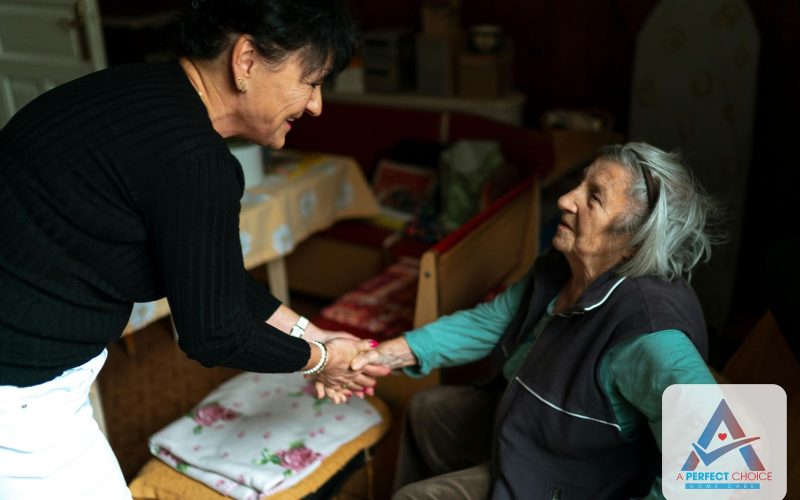 Home caregiver from A Perfect Choice greeting a smiling elderly woman at the front door of her home