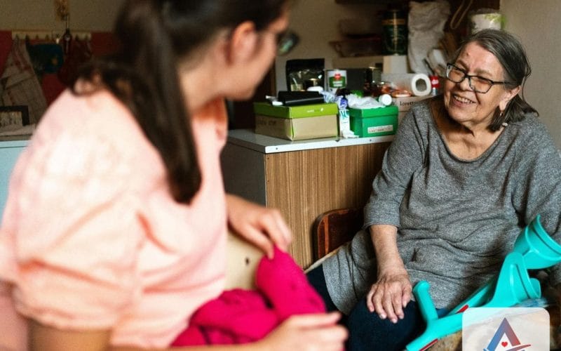 Home caregiver sitting and talking with a smiling senior woman during an in-home care visit in Southwest Florida